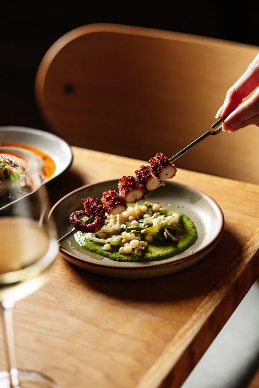 Grilled octopus skewer over herb purée