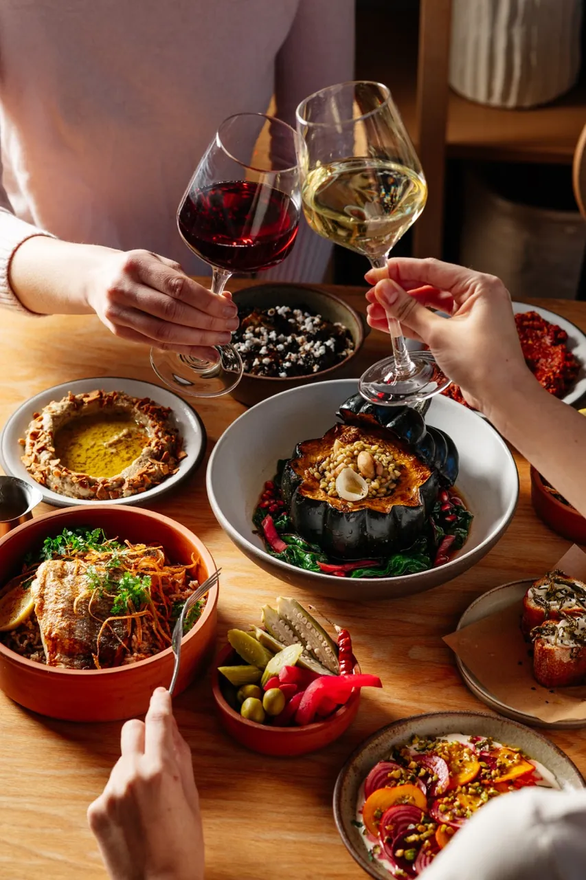 Friends toasting over roasted acorn squash and mezze